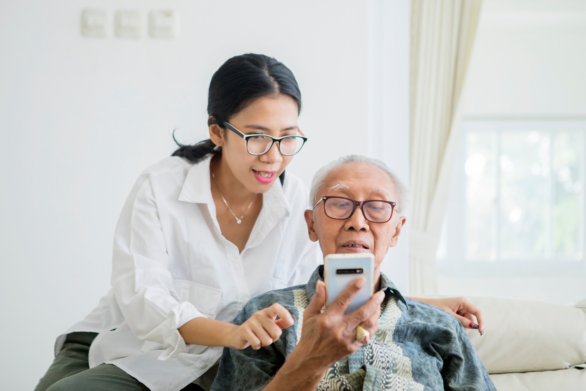 daughter helping father use smartphone