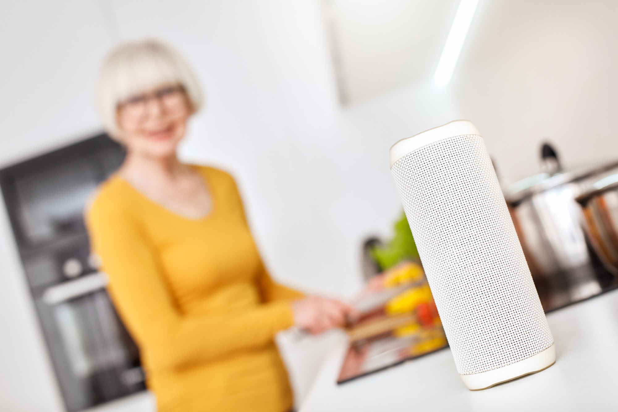 senior woman using smart speaker in kitchen